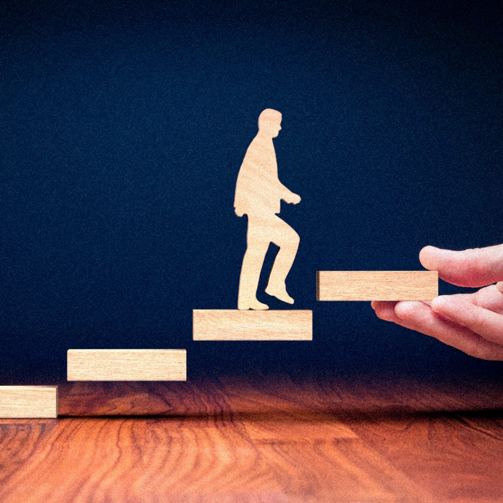 Eine Person steigt mit Unterstützung einer anderen Person eine Treppe hoch.